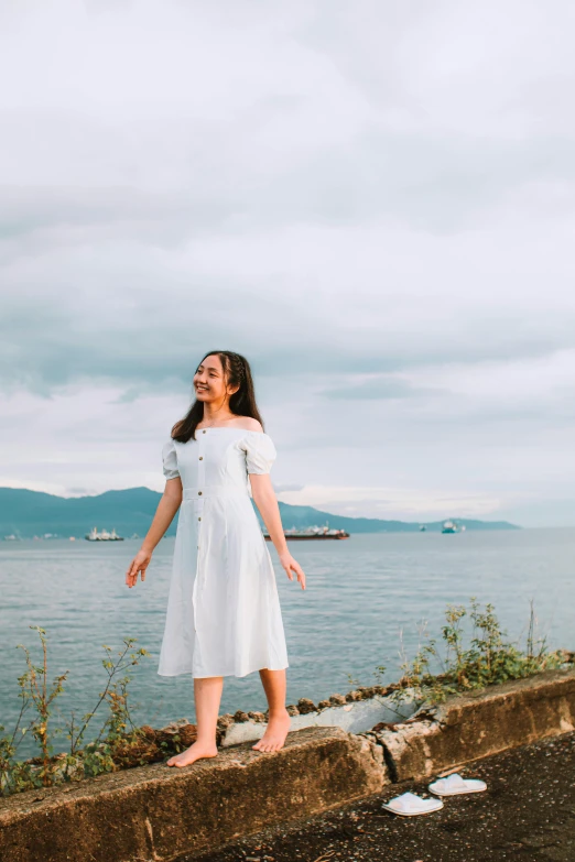 a woman in white dress posing for picture next to the water