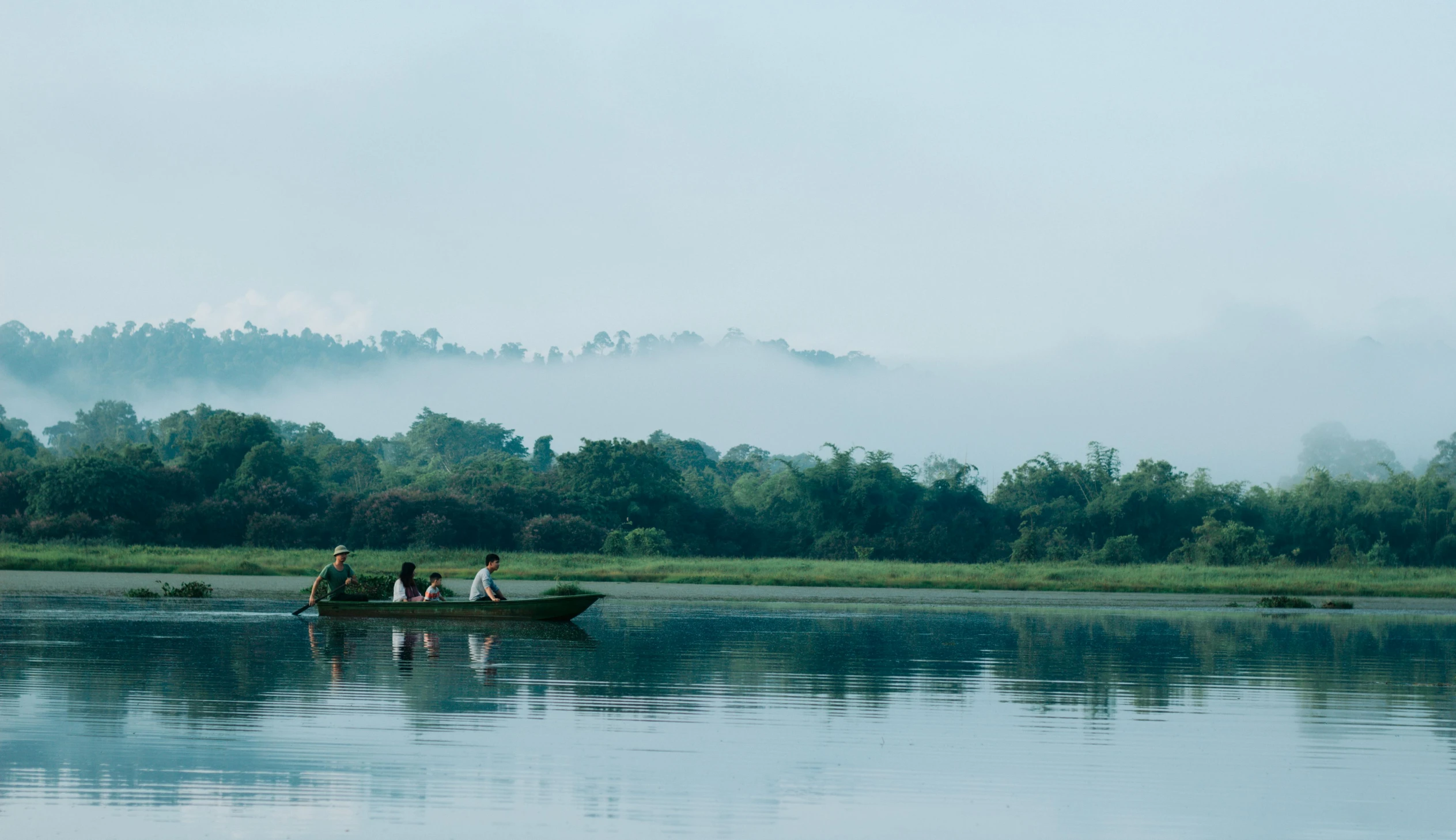 two people sit in the front row boat on the lake