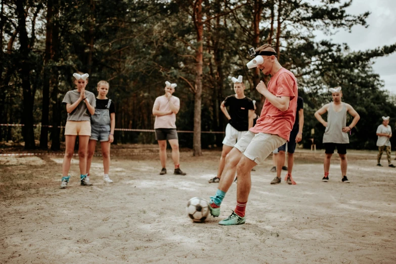 group of people in the woods playing with a soccer ball