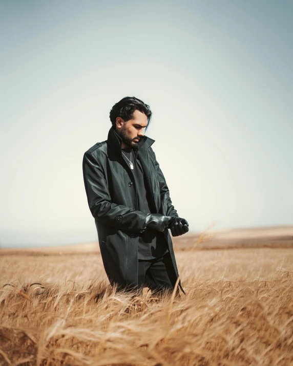 a man in black jacket standing in tall dry grass