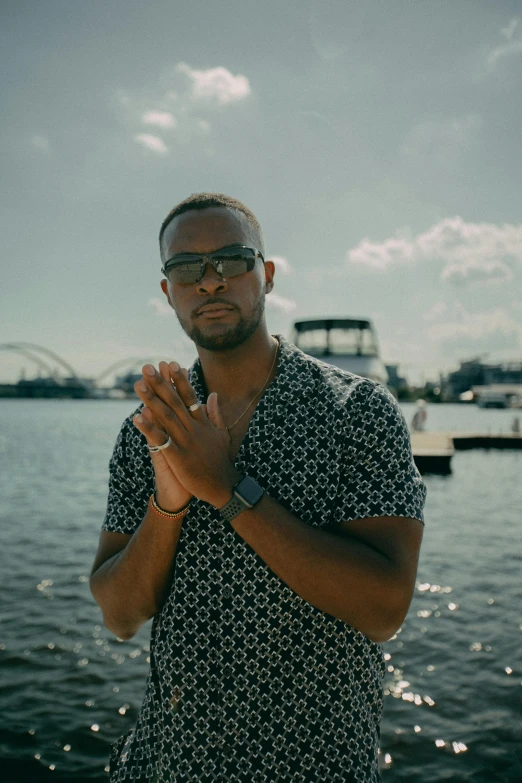 a man standing next to the water and wearing glasses