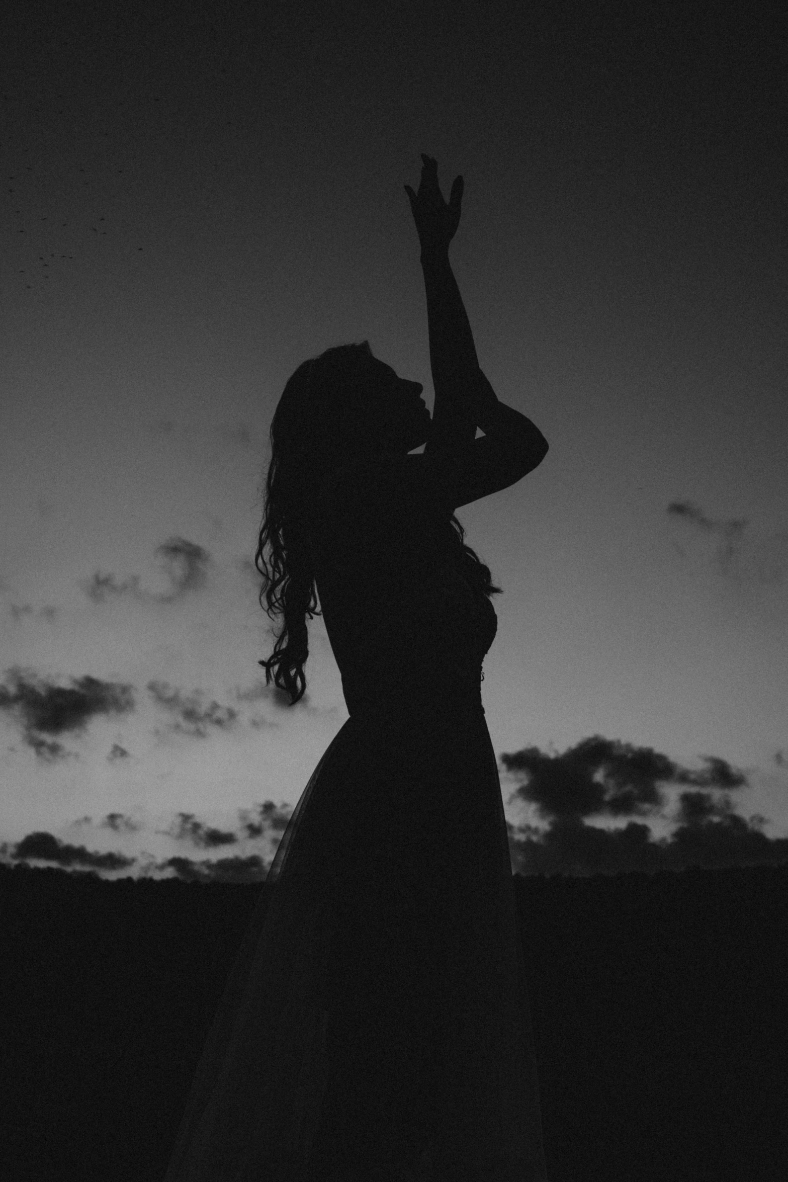 a woman with her hand up is looking at the sky