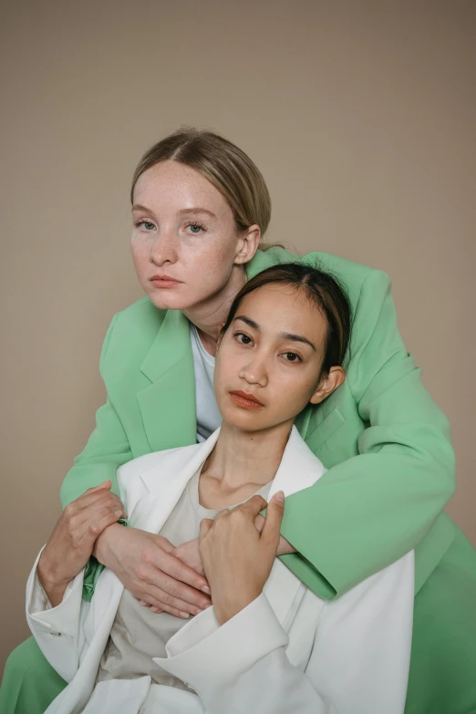 a woman in a green jacket is putting on another woman's green jacket