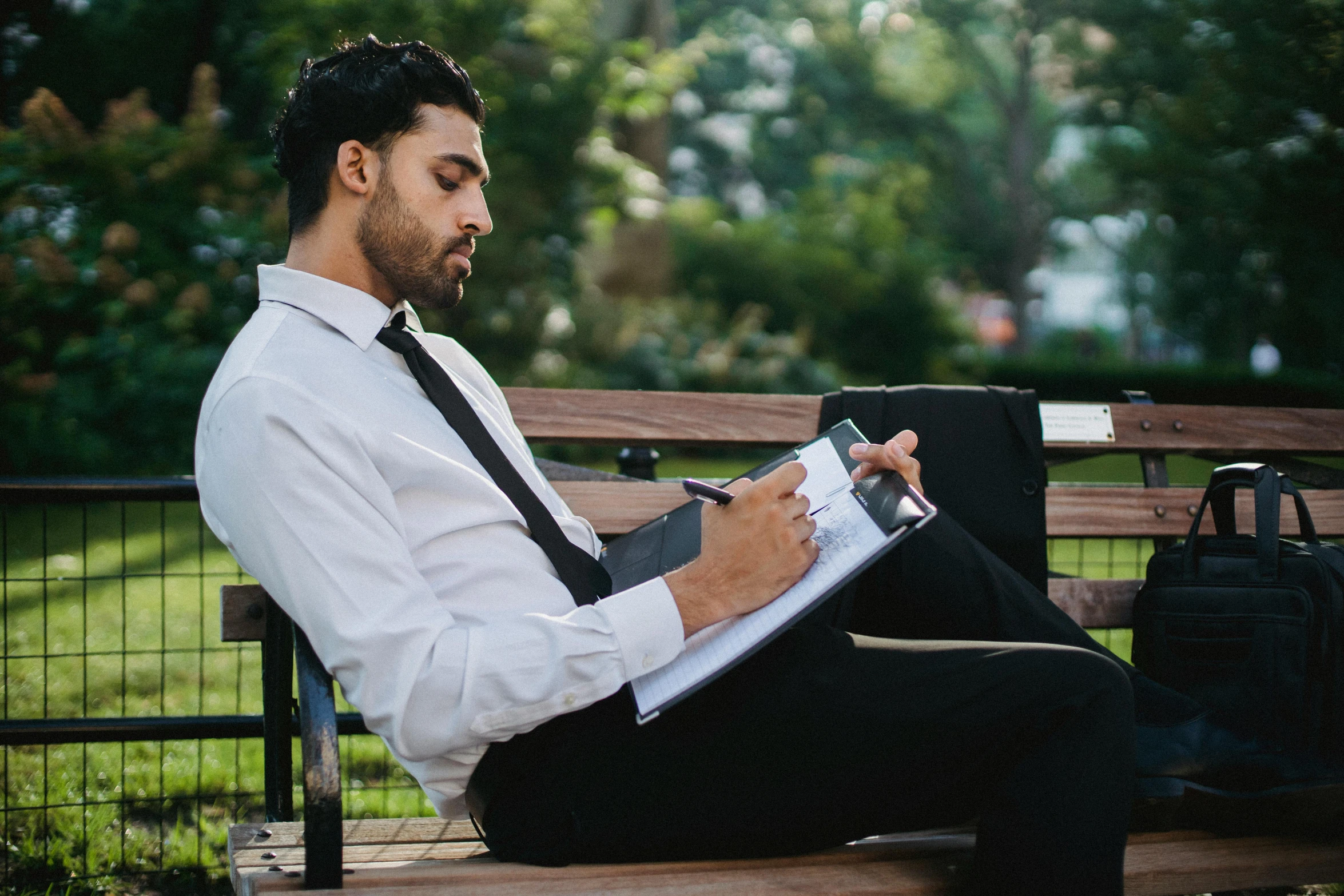 man sitting on bench holding a file folder