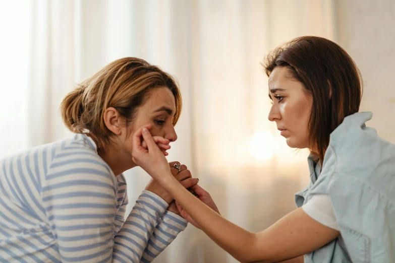 two women stand together touching noses with each other