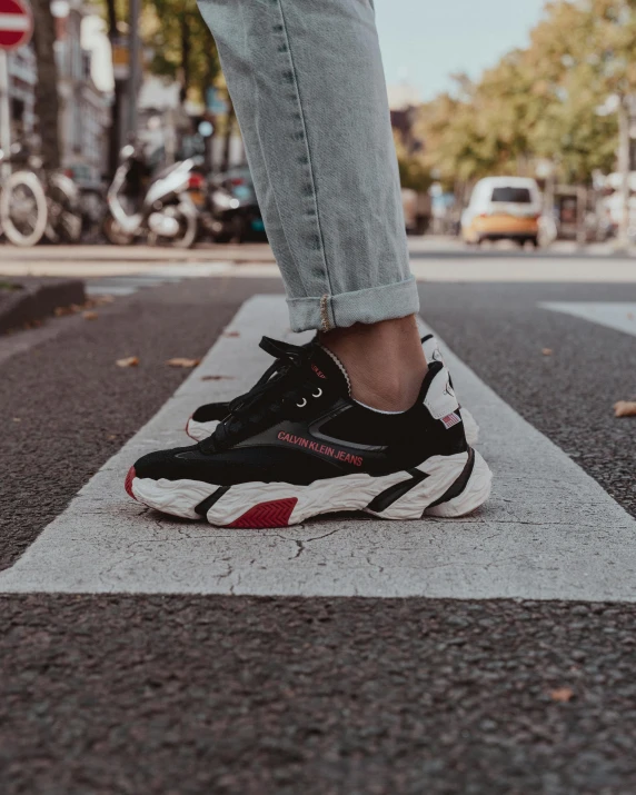 a person in white pants and black and red sneakers