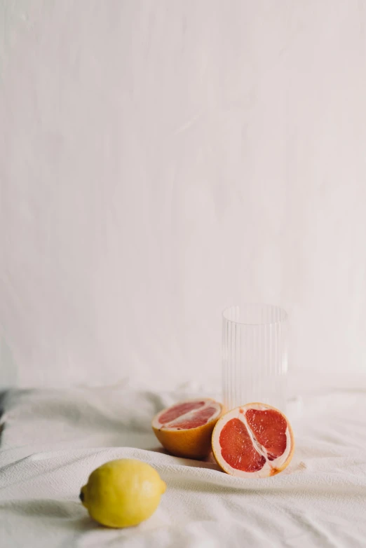 a gfruit and oranges placed next to a clear glass