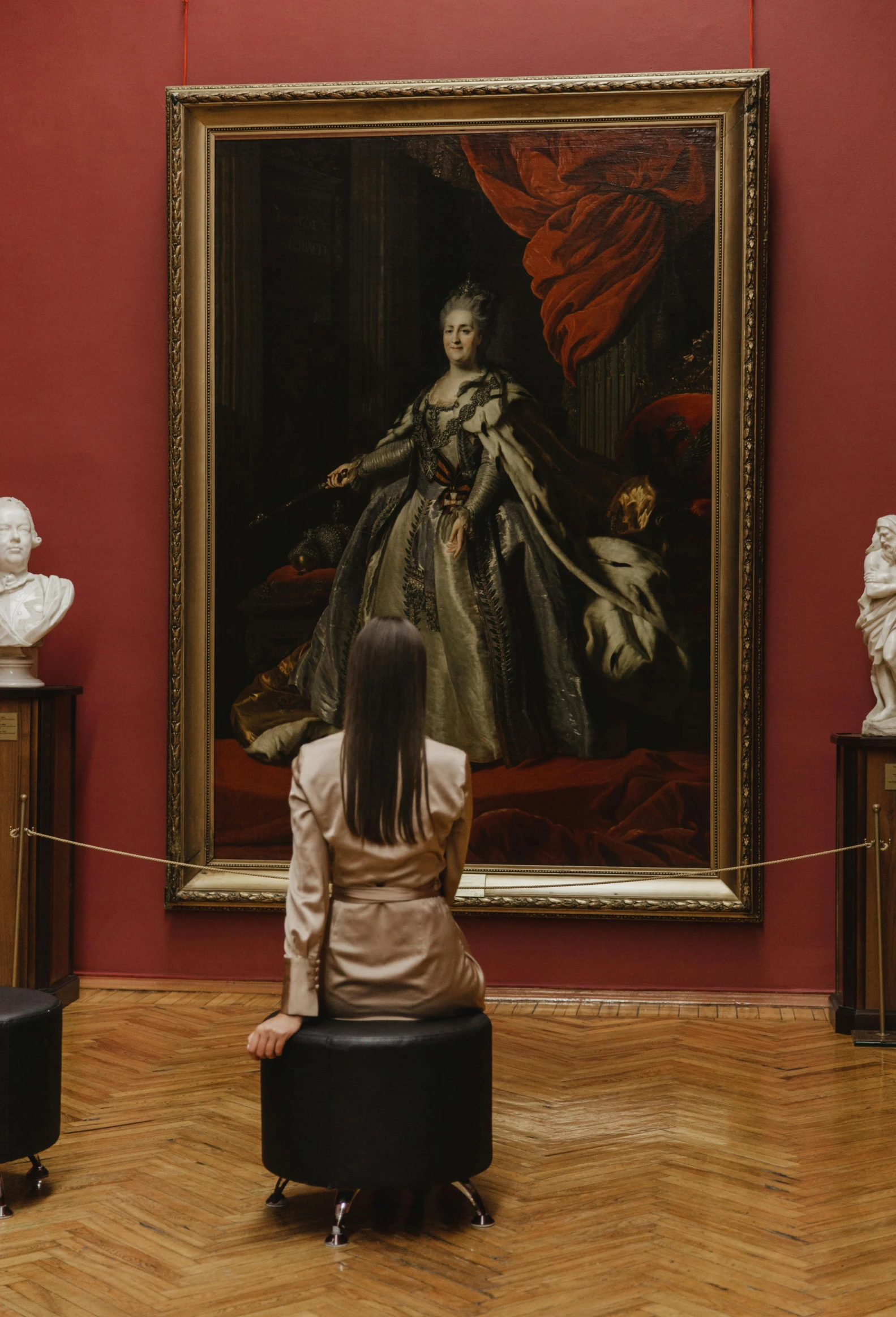 a woman sitting in front of a painting looking at a dress