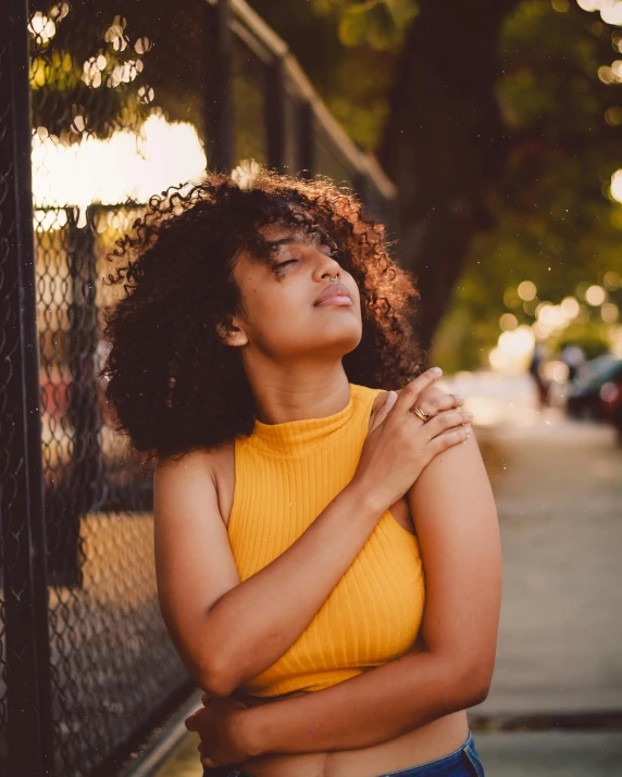 a woman with curly hair leaning against a fence