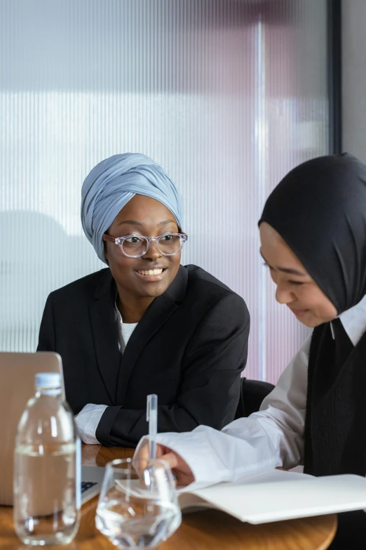 a woman sitting at a table next to another woman in a black suit