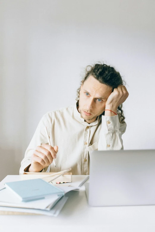 a man looks concerned at his laptop on a table