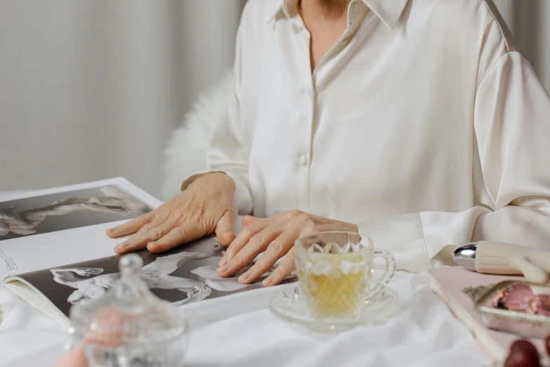 a woman sitting at a table with a cup of tea in front of her