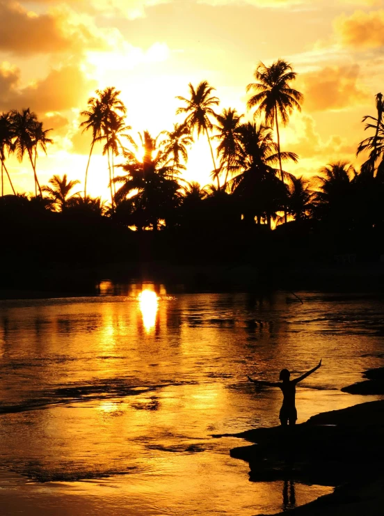 a person on a surfboard in a river at sunset