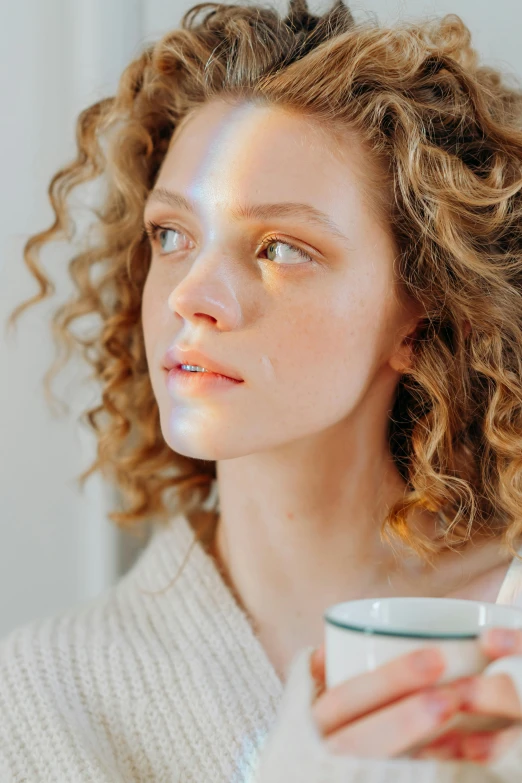 a young woman is drinking from a coffee cup