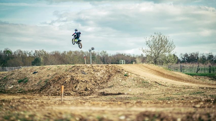 a motorcycle rider doing a jump over a hill on the road