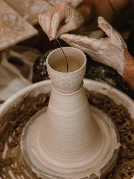 a person is preparing a vase on top of a pottery wheel