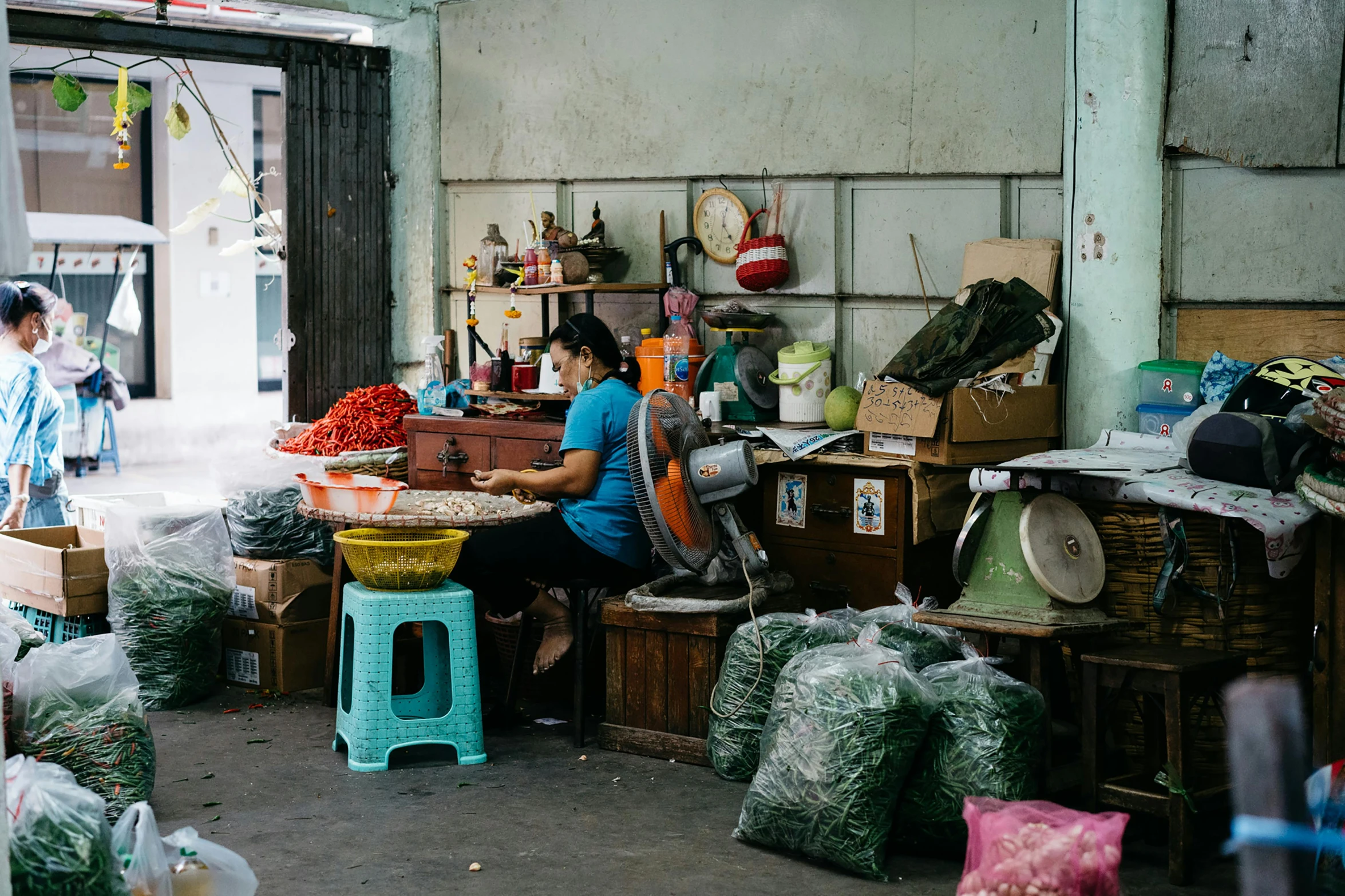 a woman sitting on stool next to a table filled with items