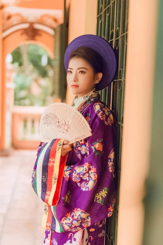 an asian woman is dressed in colorful clothes and holding her oriental fan