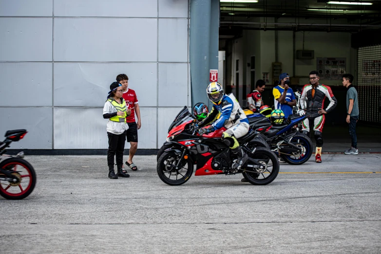 a row of men in racing suits standing near motorcycles