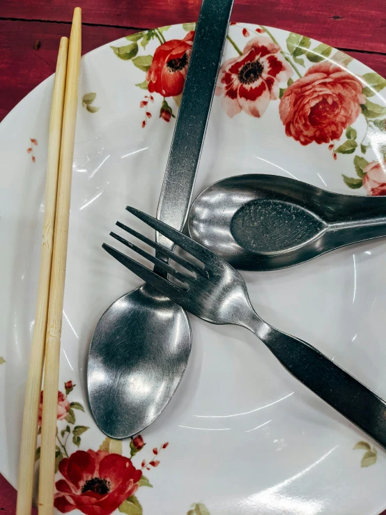 two silver forks and knives are sitting on a floral plate