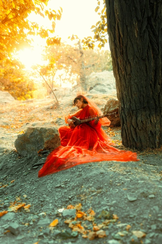 a woman wearing a red dress sitting under a tree