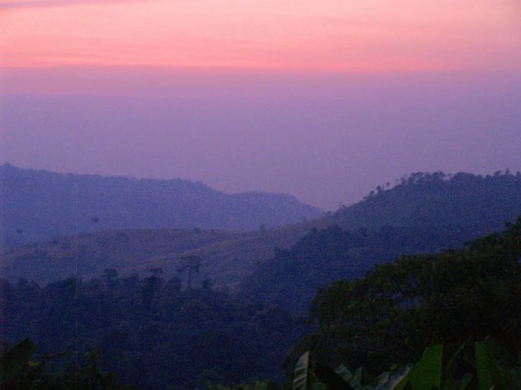 the mountains and trees are on a purple sky