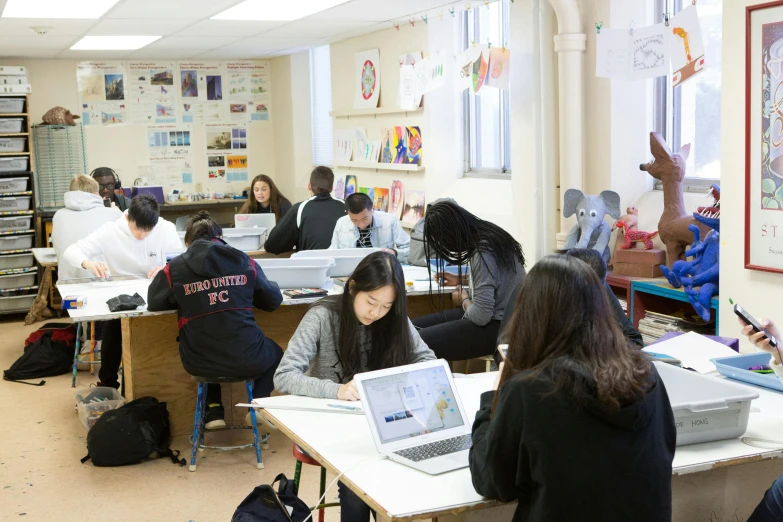 people in classroom setting with laptop computers on the desk