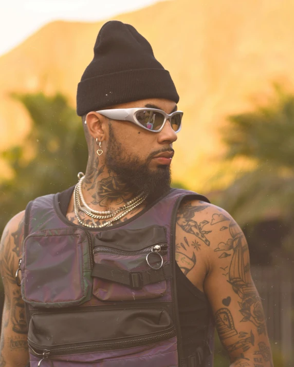 tattooed man wearing an all black outfit and sunglasses