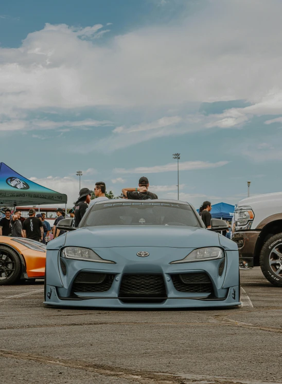 two sport cars sitting in the lot next to a large crowd