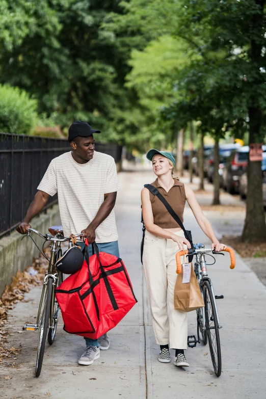 a man carrying a red bag walks beside a woman