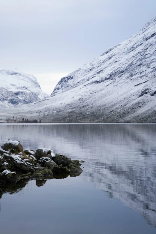 the snow covered mountains are reflected in the still water