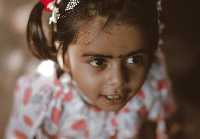 a little girl wearing a headband with flowers on her hair