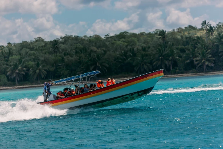 a colorful boat on the water in front of some trees