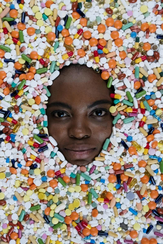 an african american female in white hood surrounded by sprinkles and pills