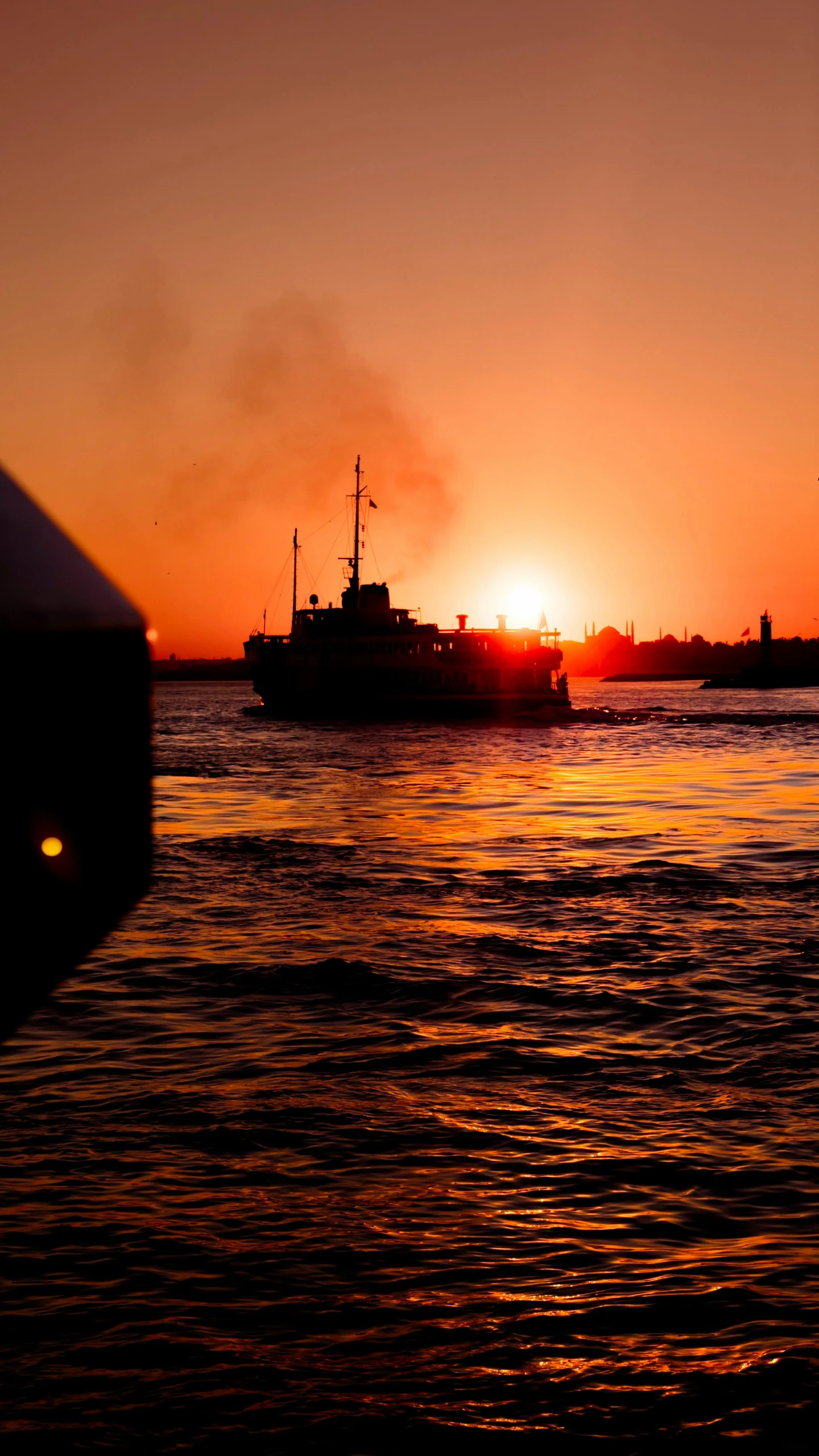 a ship in the water in the distance at sunset