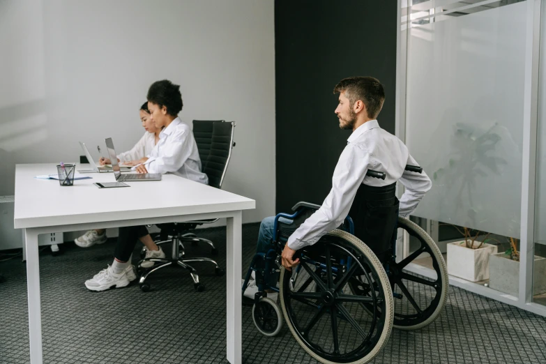 a man sitting in a wheelchair as another gentleman stands next to him