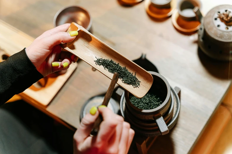 a woman holds a spoon next to a container with various spices