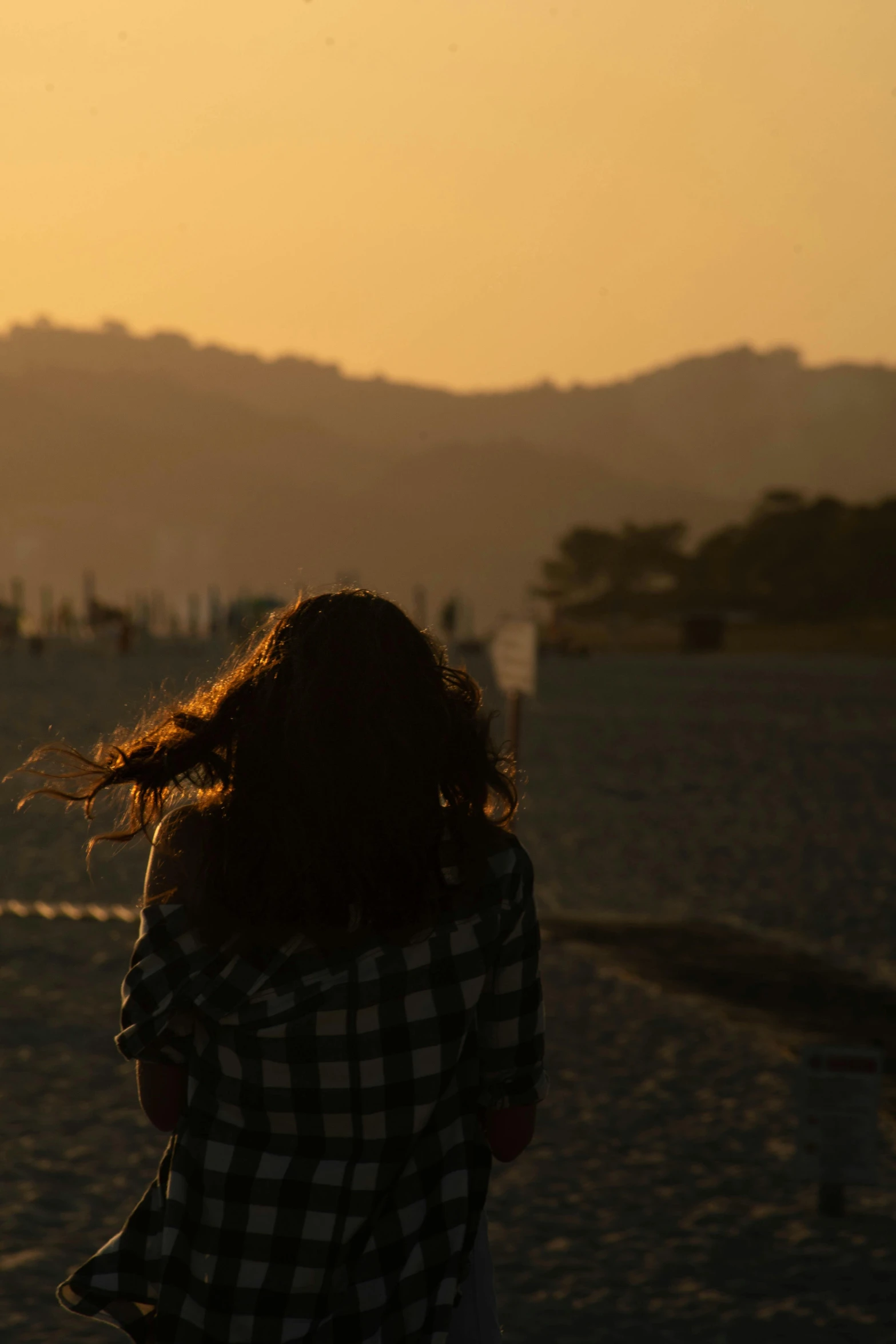 a girl in checkered jacket standing on beach near airplane