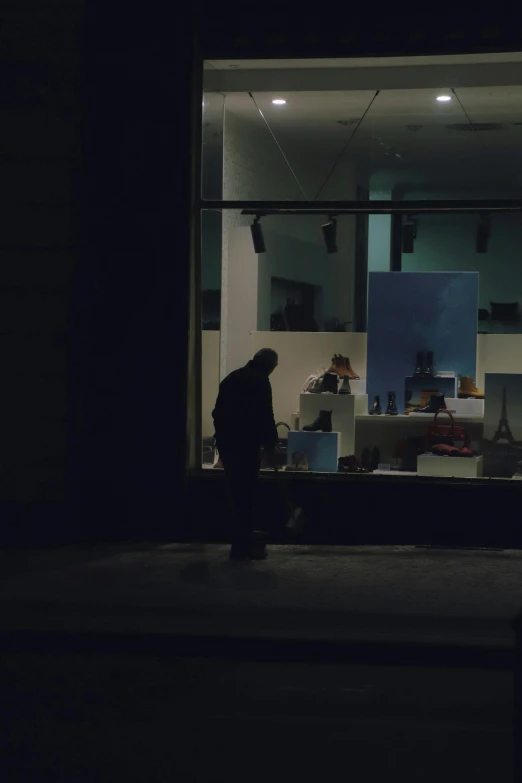 a person walking away from a store in the dark