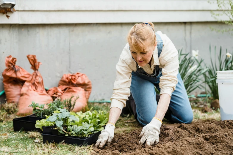 a woman is digging soil in her yard