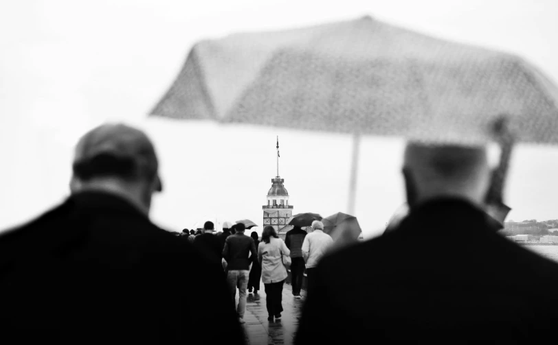 several men in black and white standing under an umbrella