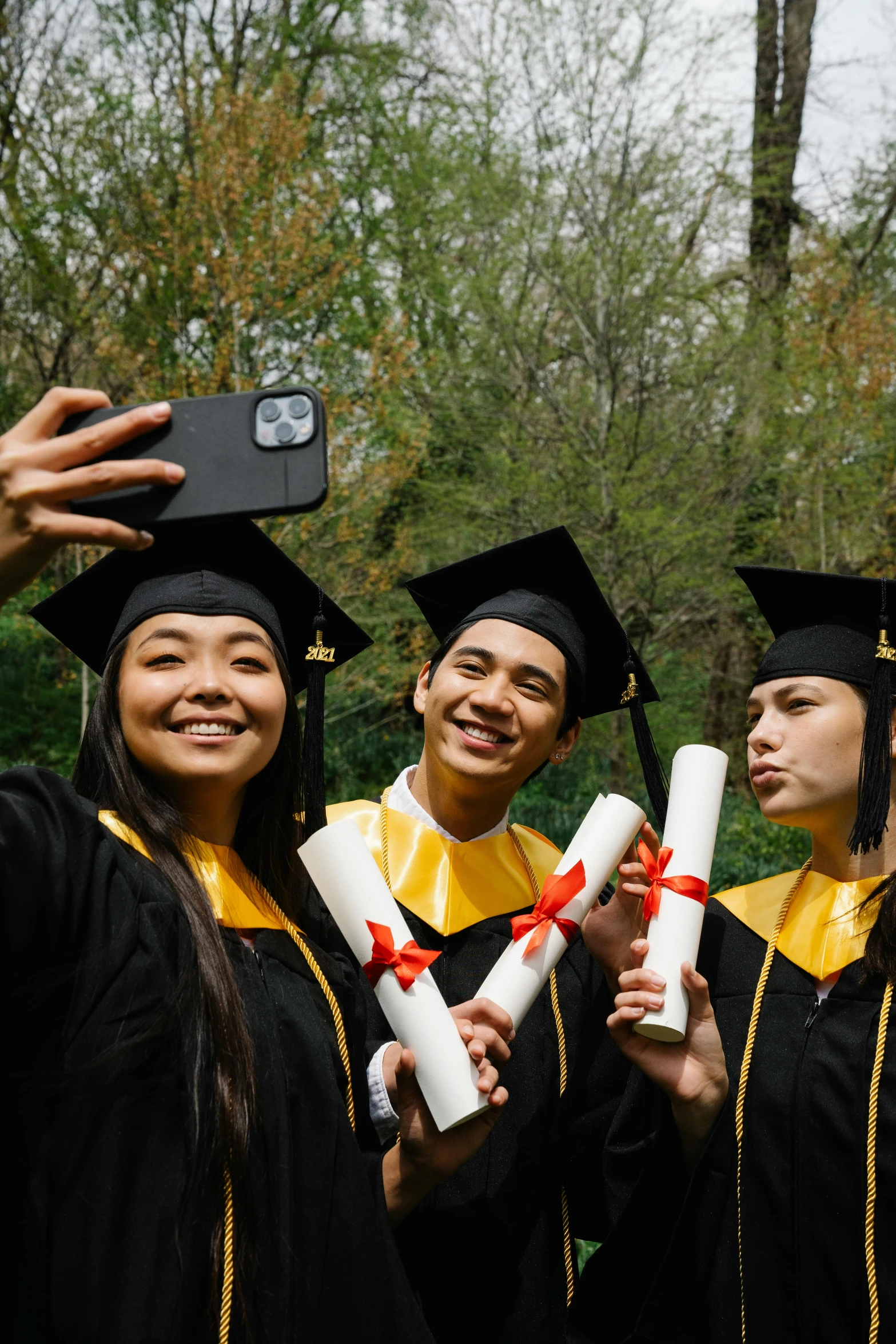 some women dressed in graduation gear, and taking a po with their camera