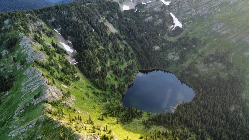 the area of the mountain has a lake surrounded by evergreen trees