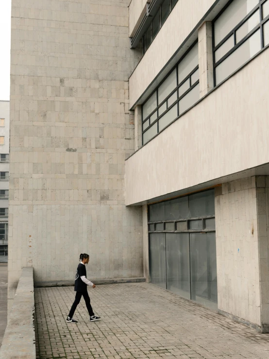 a man walking on the sidewalk in front of a building