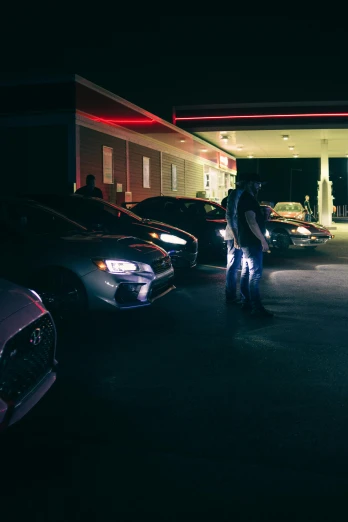 a person standing in the dark beside a bunch of parked cars