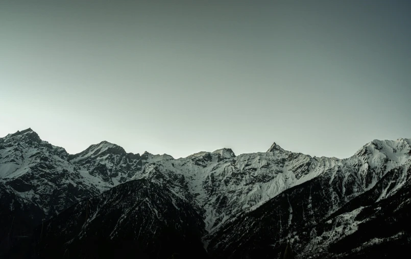 a large mountain range with two skiers on the top of it