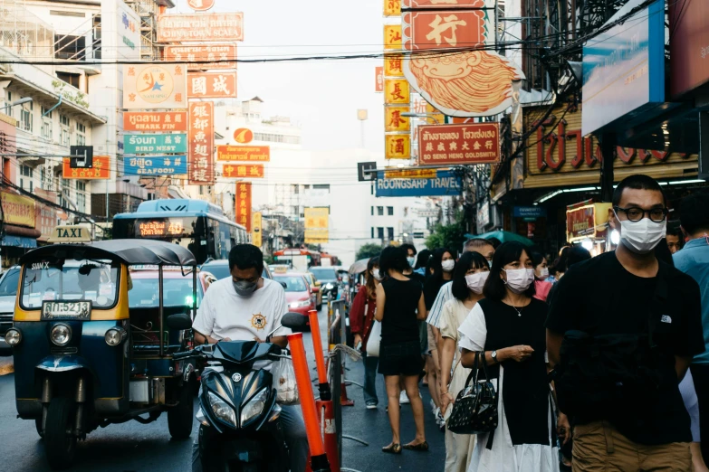 people wearing face masks on the side walk in an asian street