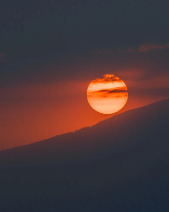 a sunset seen on top of the mountain in a very cloudy sky