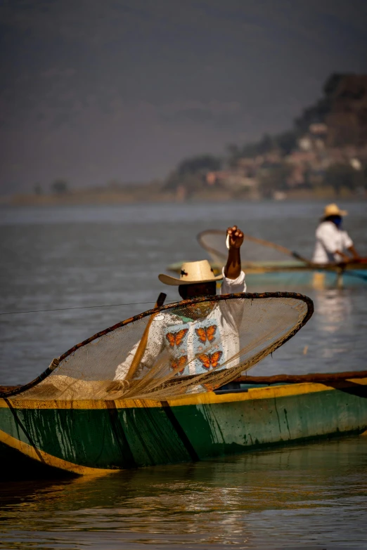 two people with hats paddling a boat in the water