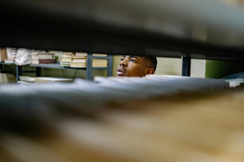 a man in a bookshelf staring up at the ground